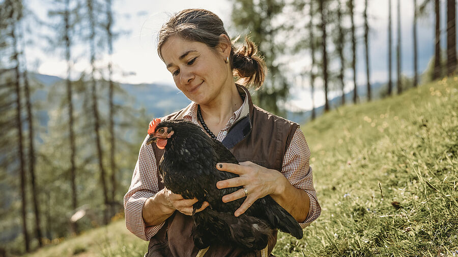 Natascha Rimbrecht auf der Bergwiese mit einem Huhn
