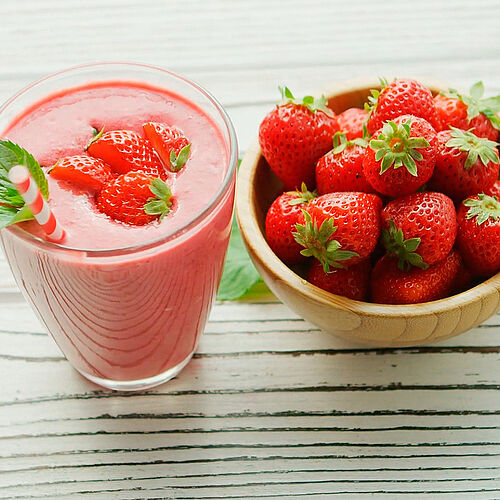 Darstellung Schale mit frischen Erdbeeren und Glas Erdbeer-Ziegenmilch-Shake
